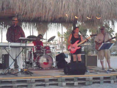 The Kiri Mariposa Band performing outdoors under a palapa