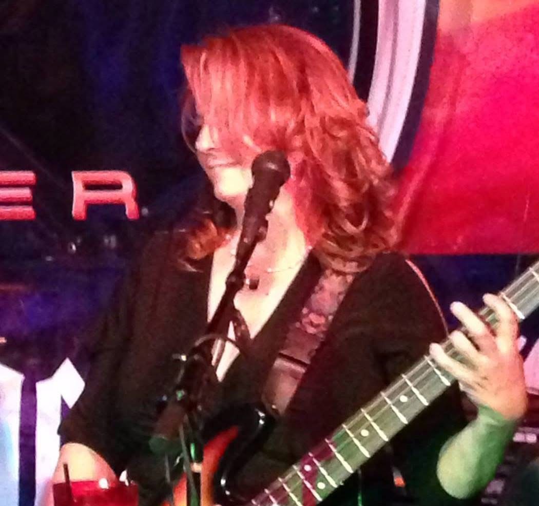 Kiri Mariposa Hall playing bass and singing under stage lights